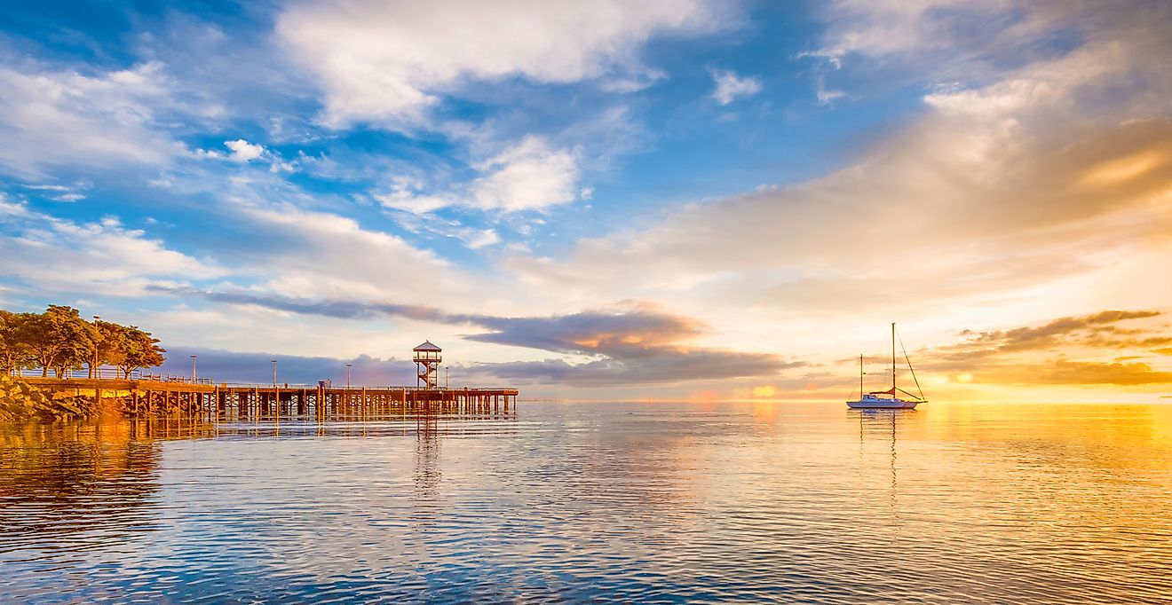 A boat anchored on the calm waters of the Puget Sound as the early morning sun rays warm the cloud ridden sky at Port Angeles, Washington.