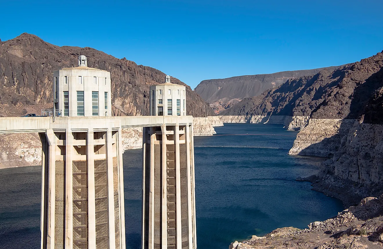 Detailed view of the Hoover Dam intake towers standing above the Colorado River, showing water levels and surrounding rocky desert terrain