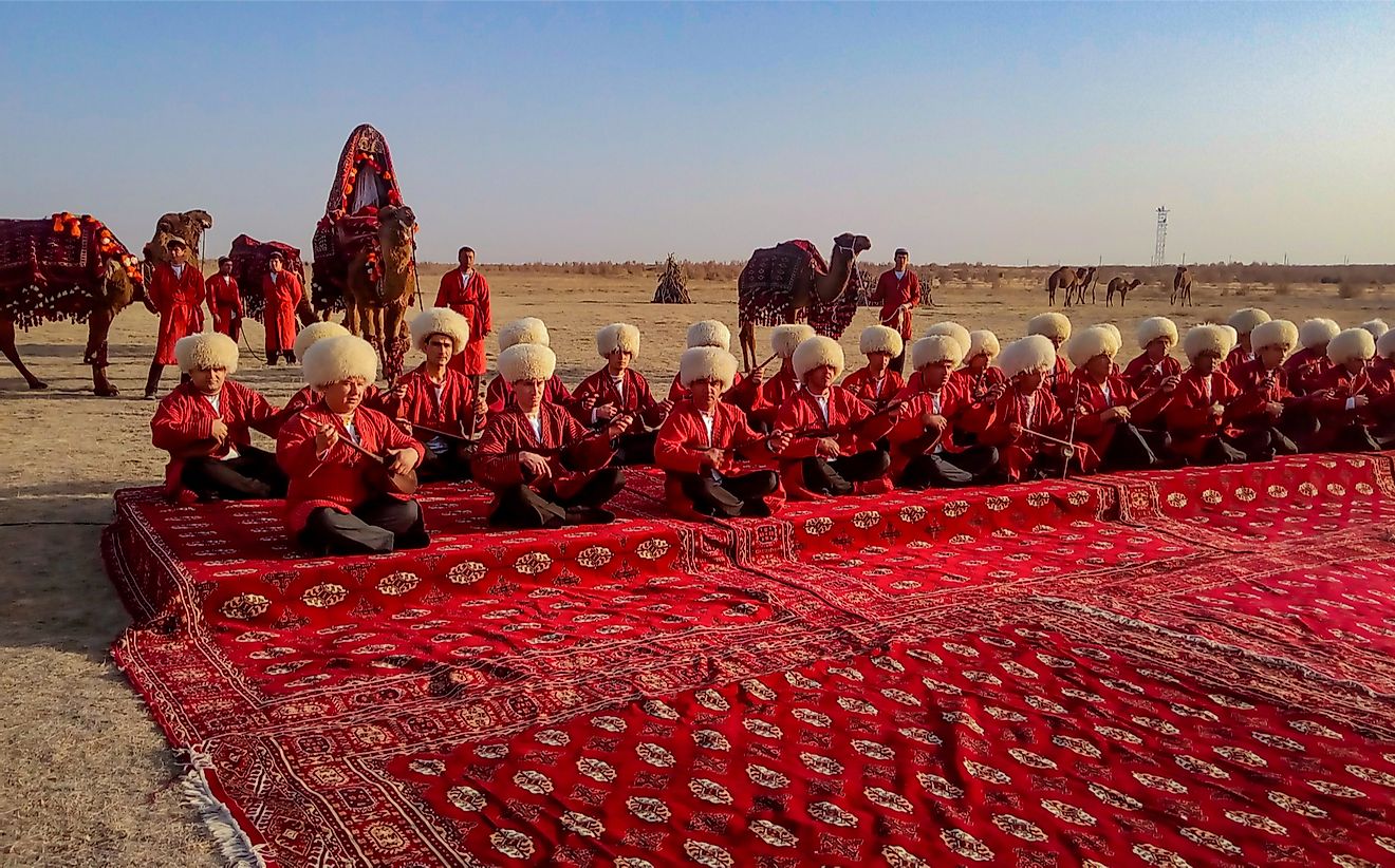 Turkmen sit on a traditional carpet playing musical instruments in Turkmenistan. Olga Nikanovich / Shutterstock.com.
