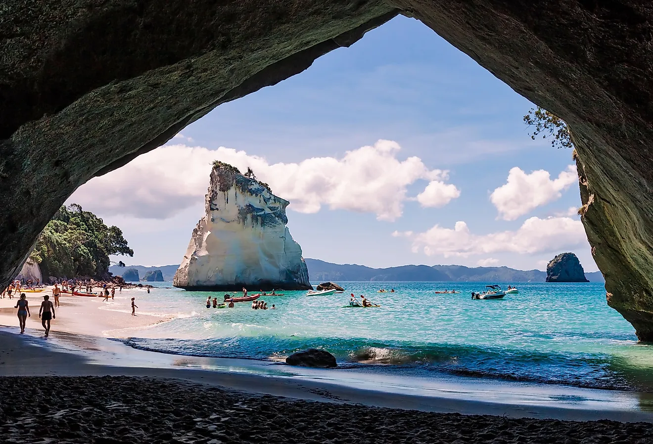 Cathedral Cove, beautiful beach with rocks and tourists in cave in Hahei, New Zealand. Image credit riekephotos via Shutterstock.com