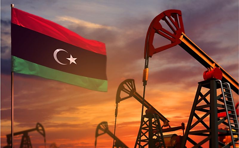 Libya flag and oil wells and the red and blue sunset or sunrise sky background.