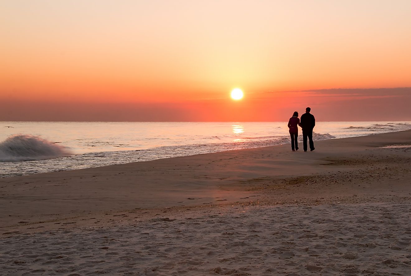 A loving couple take a stroll at sunset along the beach at Navarre Beach, Florida.