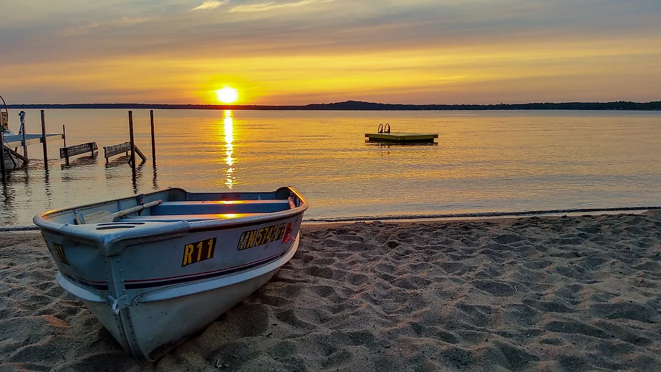 Sunset at Gull Lake, Minnesota, with row boat pulled onto sandy beach.