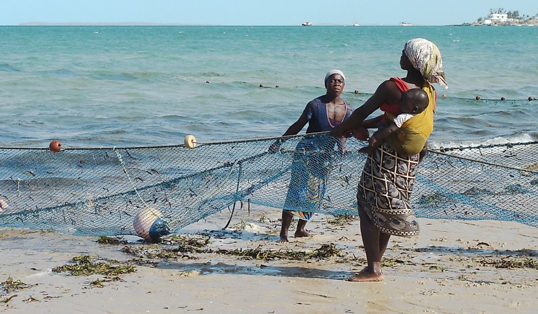 Women help pull in fishing nets in exchange for small fish in Vilanculos, Mozambique.  Editorial credit: Julia Kavtaradze / Shutterstock.com
