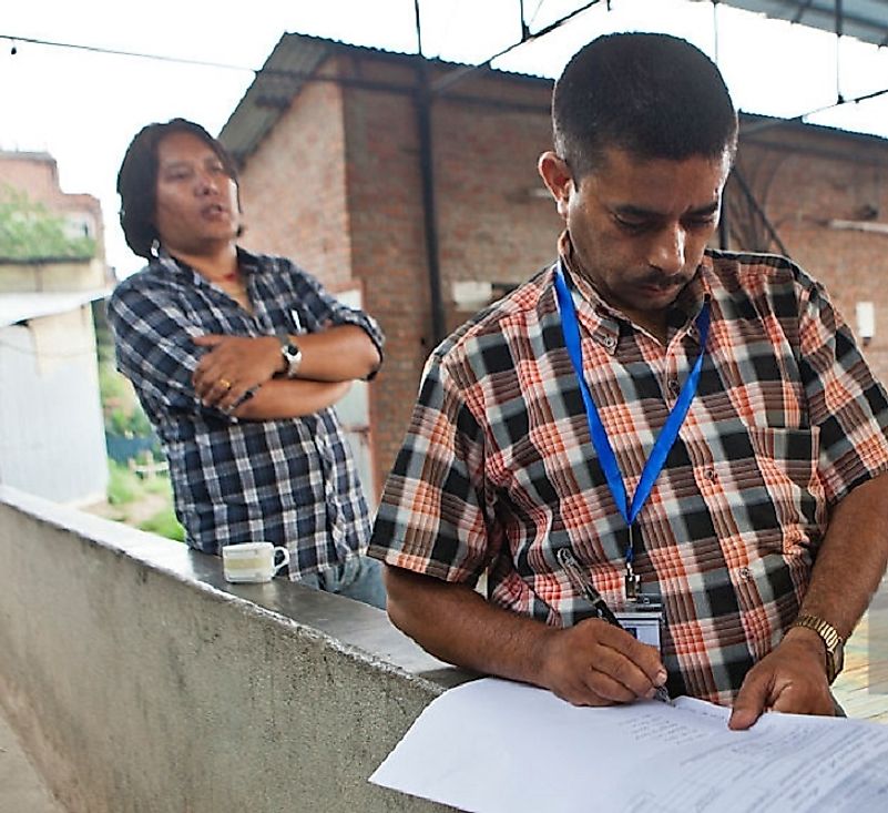 Nepalese carpet factory owners filling out forms to register their goods.