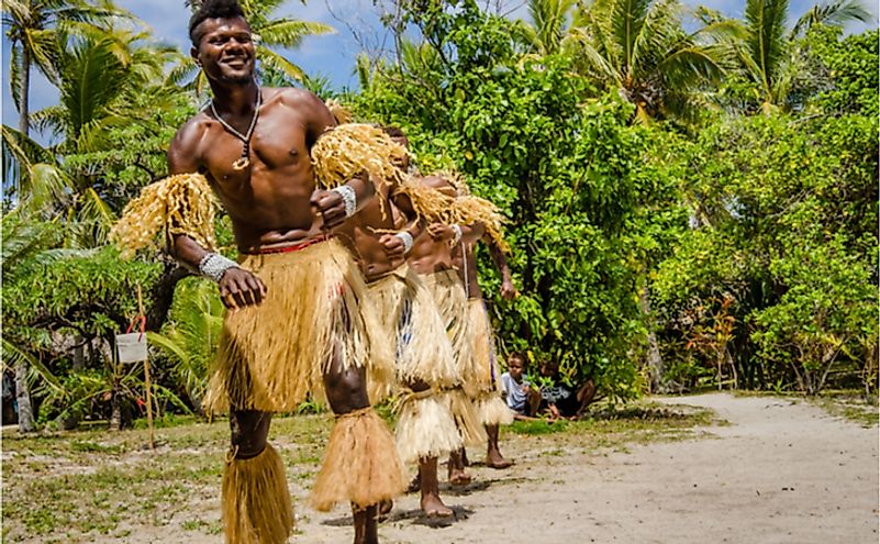 Male dancers in traditional native costumes made from grass entertain visitors from cruise ship spending the day on the uninhabited island. Editorial credit: lembi / Shutterstock.com