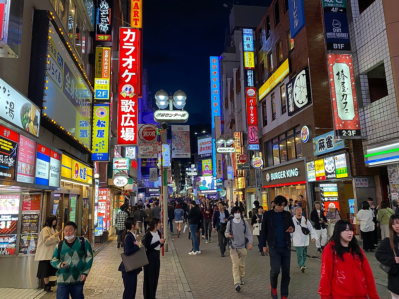 Nighttime on a crowded street in Tokyo. Neon advertisements fill the frame.