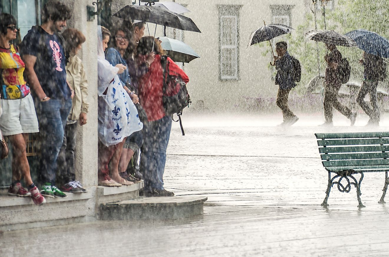 A group of people take cover during heavy rains under a building. Image credit: Andriy Blokhin/Shutterstock.com