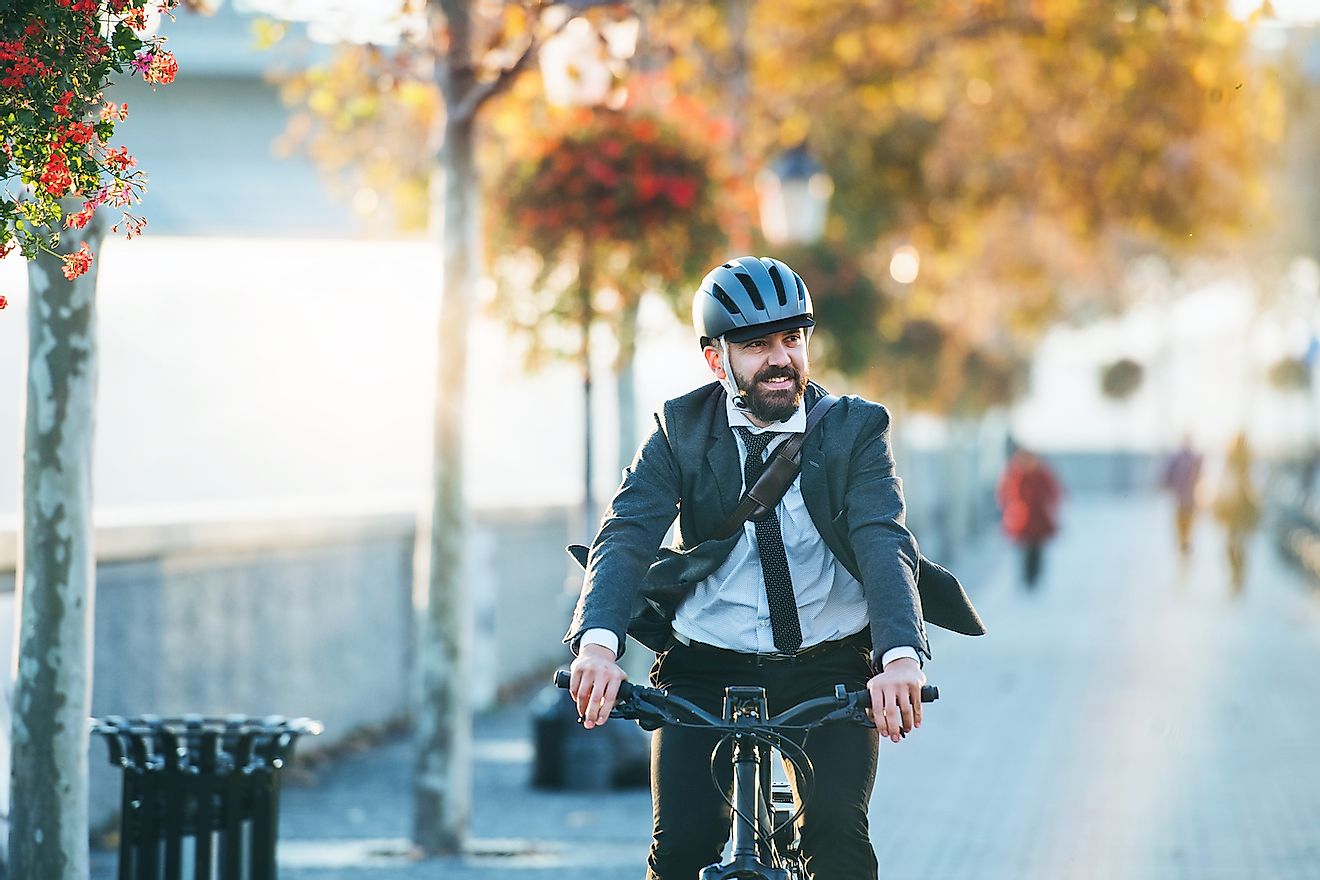 Businessman commuter with electric bicycle traveling home from work in city. Image credit: Halfpoint/Shutterstock.com