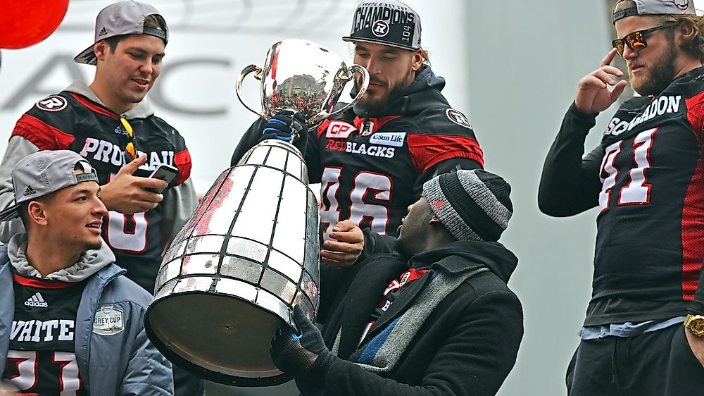 Members of the Ottawa Redblacks holding the Grey Cup. Editorial credit: Paul McKinnon / Shutterstock.com