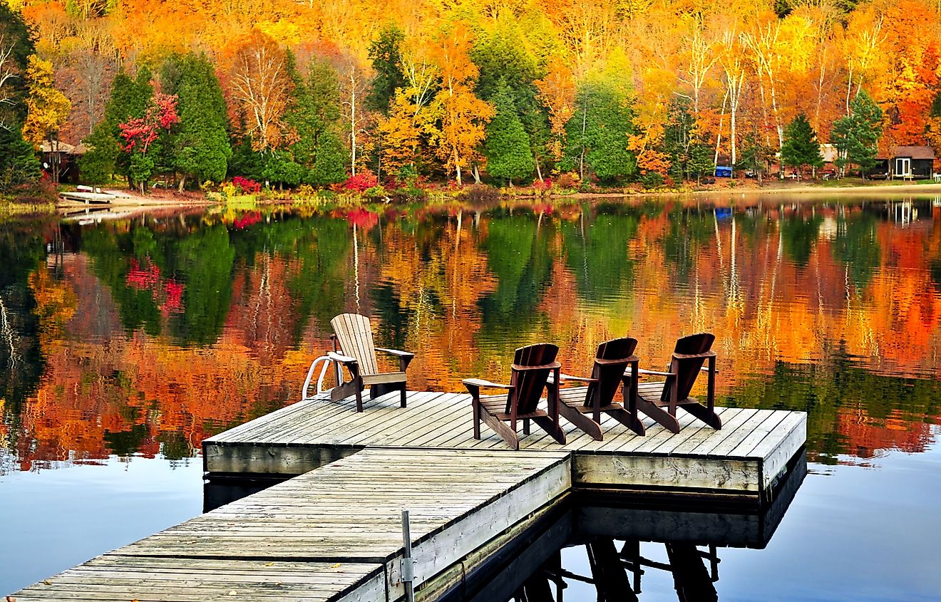 Wooden dock with chairs on calm fall lake. Image credit Elena Elisseeva via shutterstock