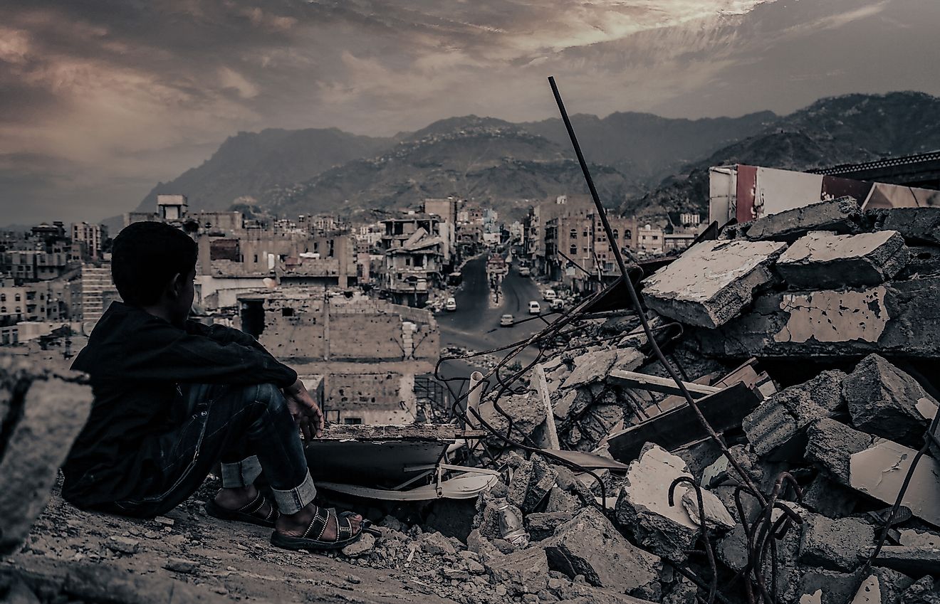 A child from Taiz City sits on the ruins of his ruined home because of the war on city-Yemen. Editorial credit: akramalrasny / Shutterstock.com