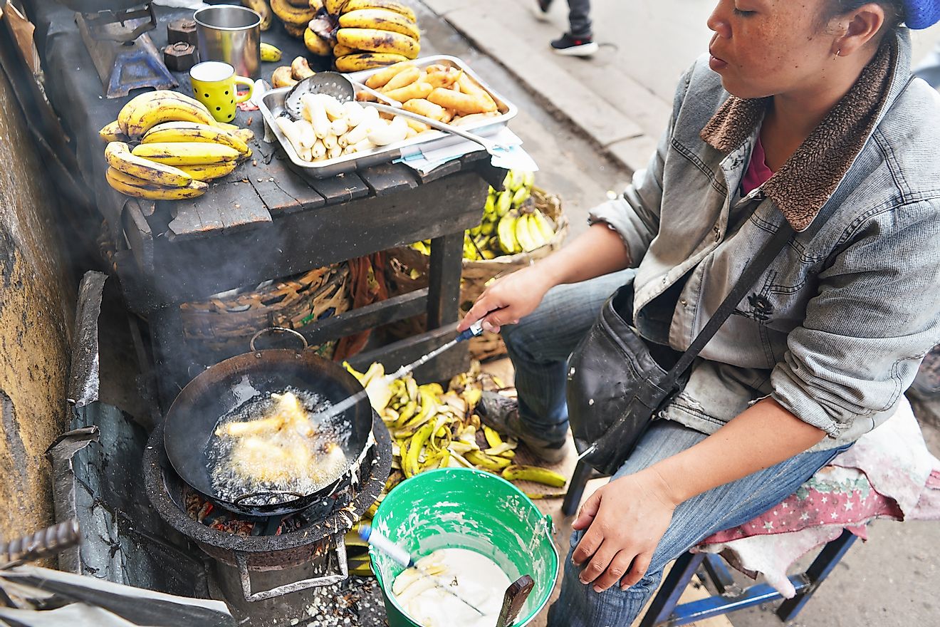 Local Malagasy woman frying bananas in oil at her stall on market next to main road. Image credit:  Lubo Ivanko/Shutterstock.com
