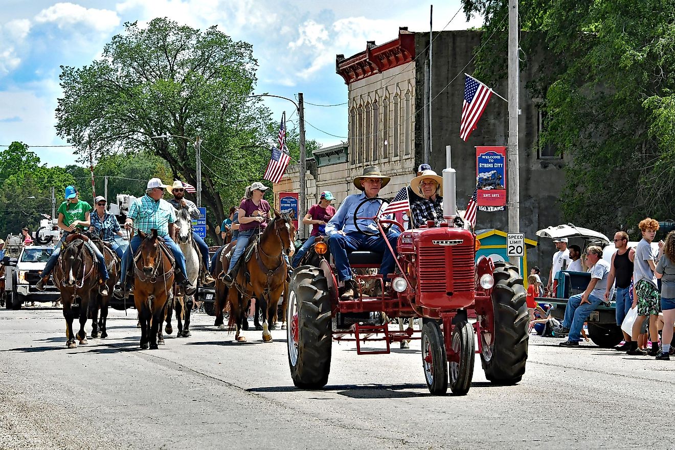 In Strong City, Kansas, USA, an elderly local farmer drives his 1939 Farmall model H tractor, leading a group of cowboys and cowgirls in the annual Flint Hills Rodeo parade. Editorial credit: mark reinstein / Shutterstock.com