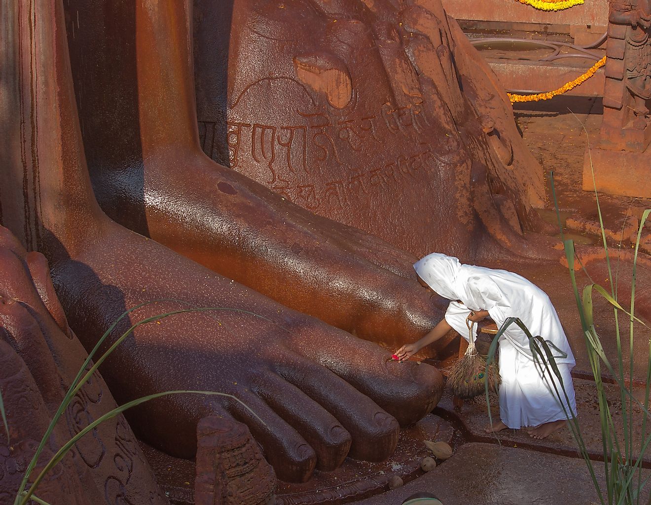 A Jain nun or Sadvi offering prayers to the gigantic feet of the monolith statue of Bahubali at Shravanabelagola near Mysuru in Karnataka / India. Editorial credit: PRIYA DARSHAN / Shutterstock.com
