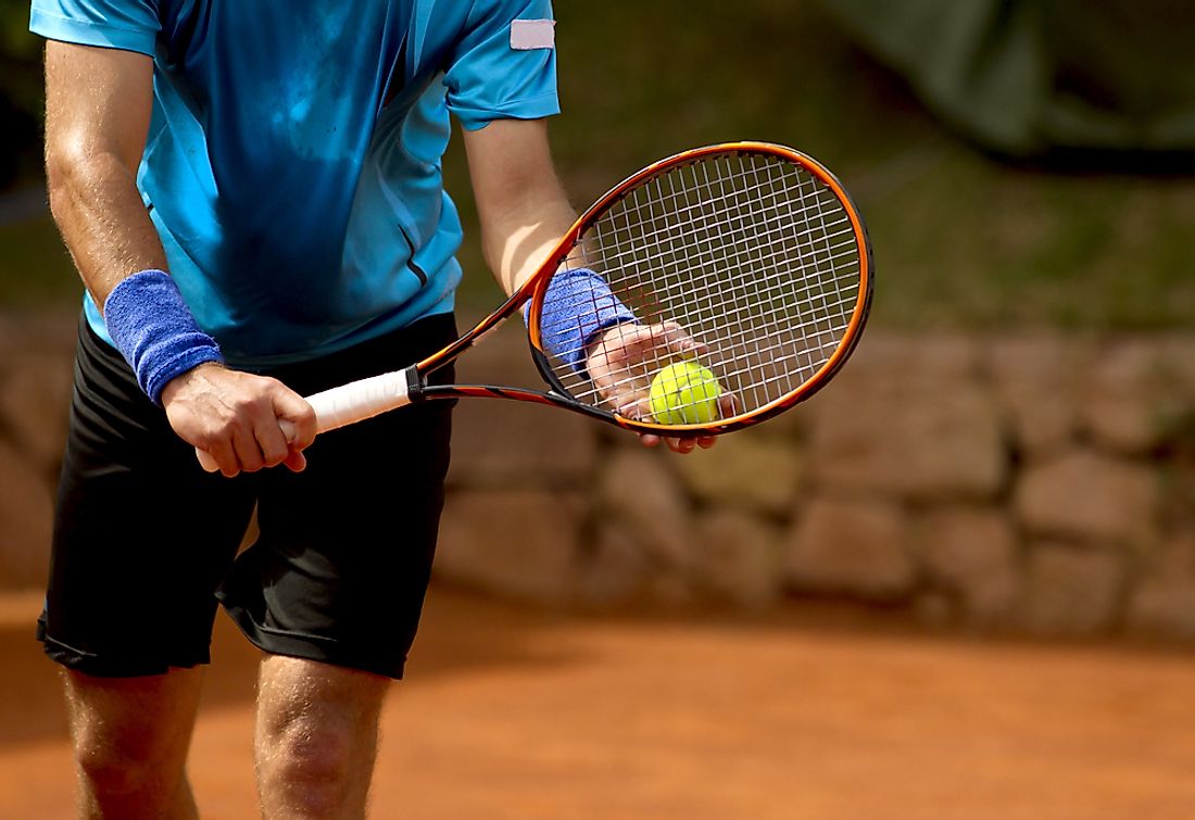 A tennis player prepares to deliver a serve. 