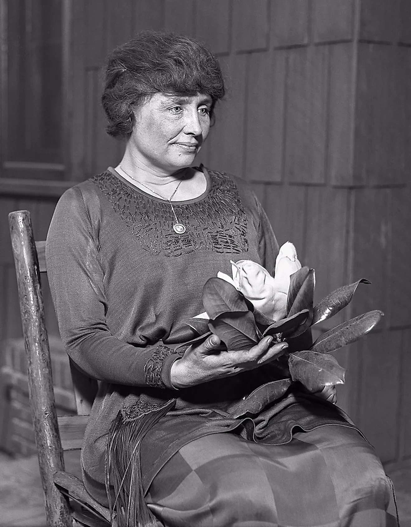 Helen Keller sitting, holding a magnolia flower, circa 1920. Image from the Los Angeles Times