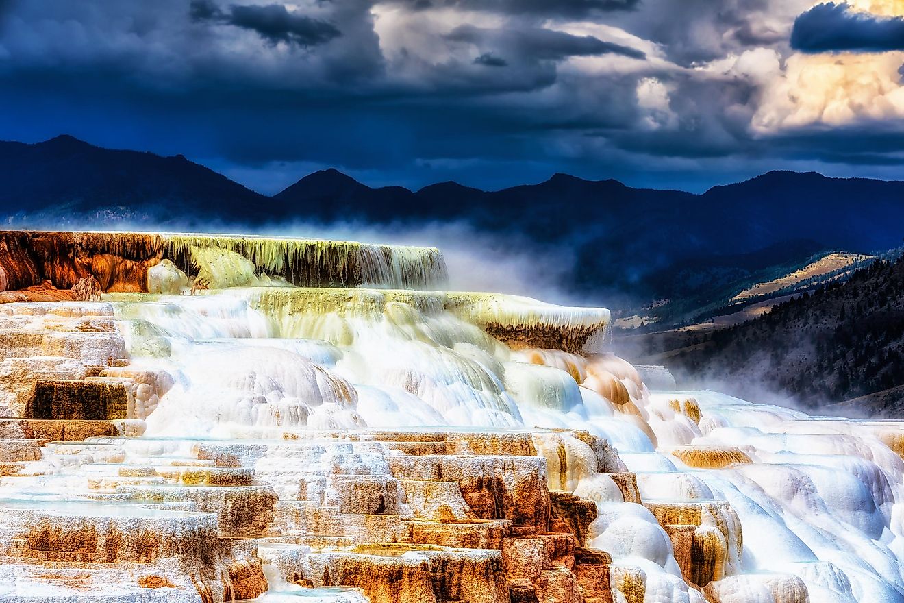 Travertine terraces at Mammoth Hot Springs, Yellowstone, under cloudy skies.