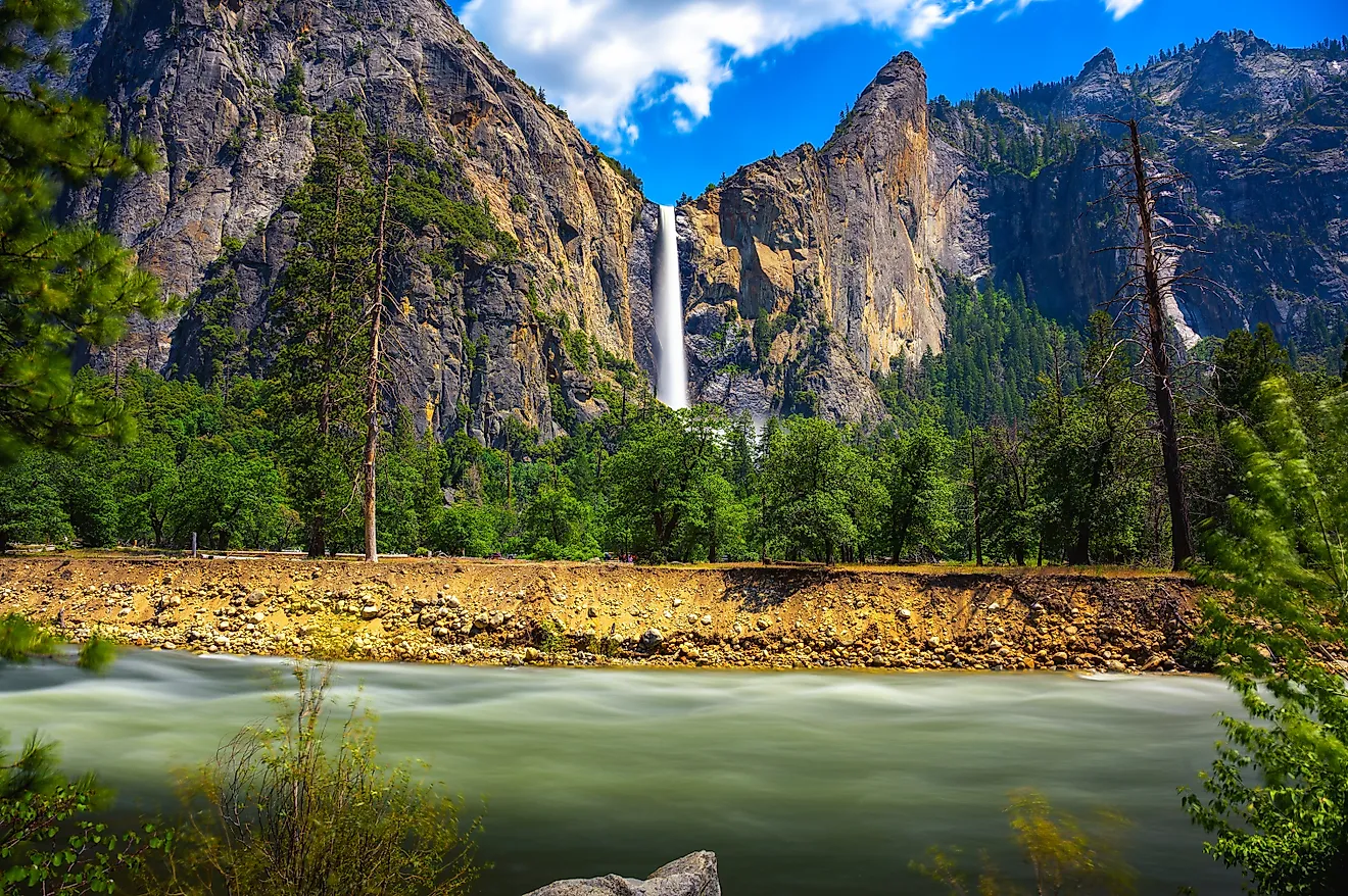 Bridalveil Fall cascading into Yosemite Valley with the Merced River in the foreground in Yosemite National Park, California. 