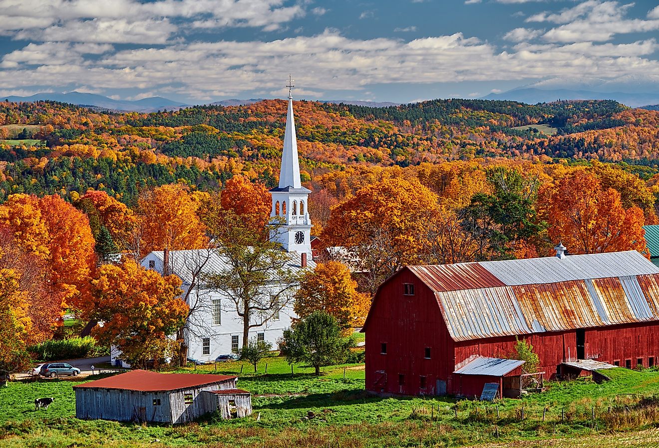 Congregational Church and farm with red barn on a sunny autumn day in Peacham, Vermont.