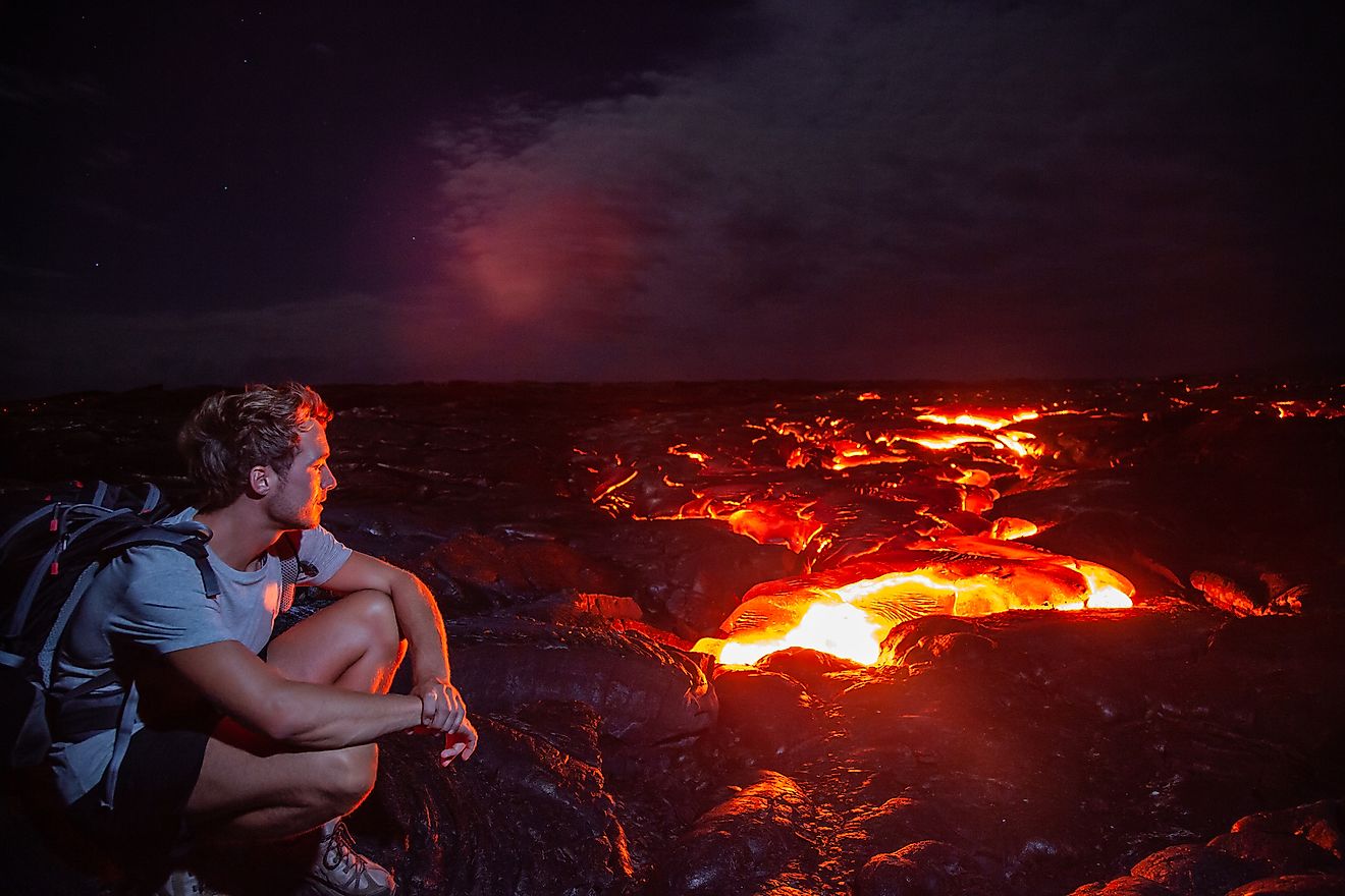 A hiker watching lava flow from Kilauea volcano