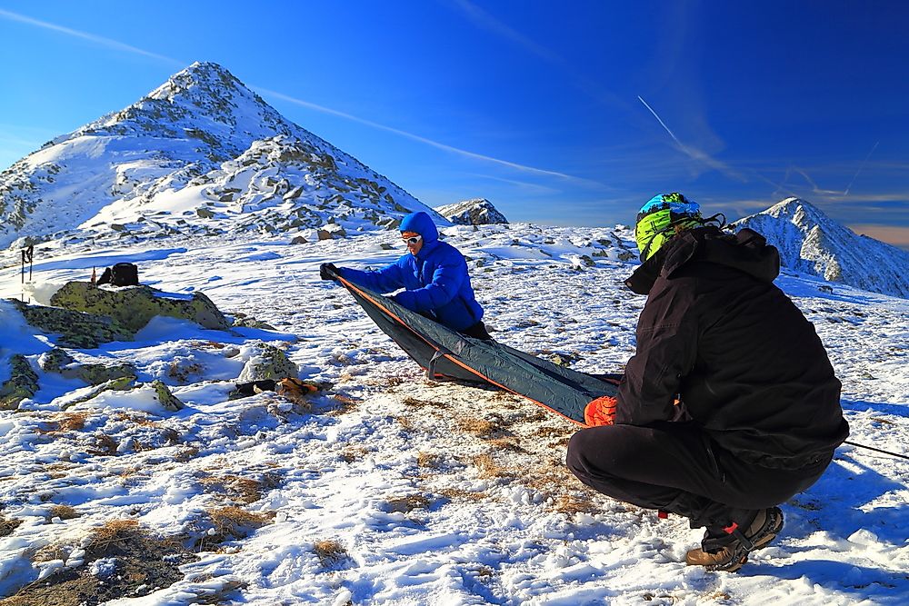 A pair of mountaineers set up a tent.