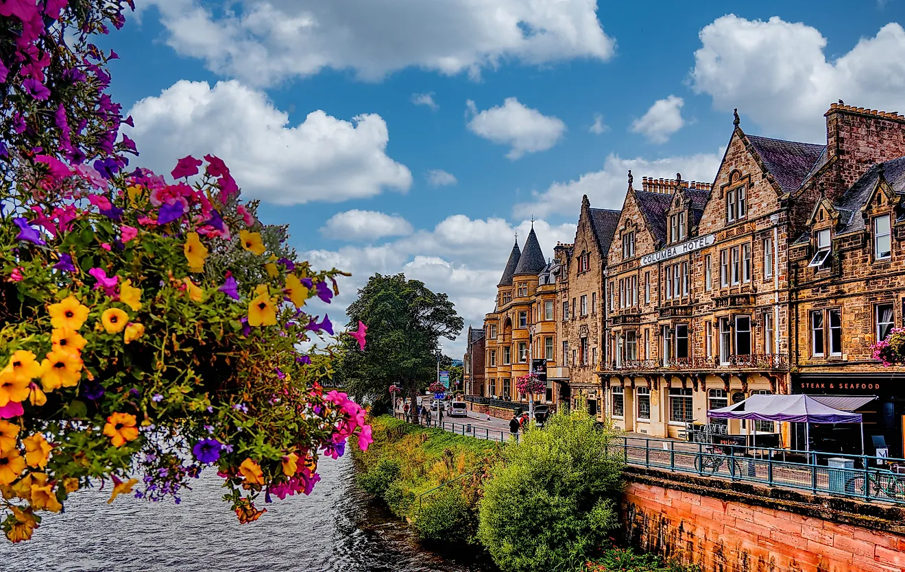 Victorian-era buildings line a busy street in Inverness, Scotland, where locals and tourists stroll amid shops. 