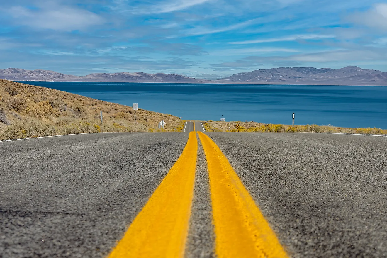 An image of the yellow lines on the road guiding to Pyramid Lake, Nevada with mountains in the background.