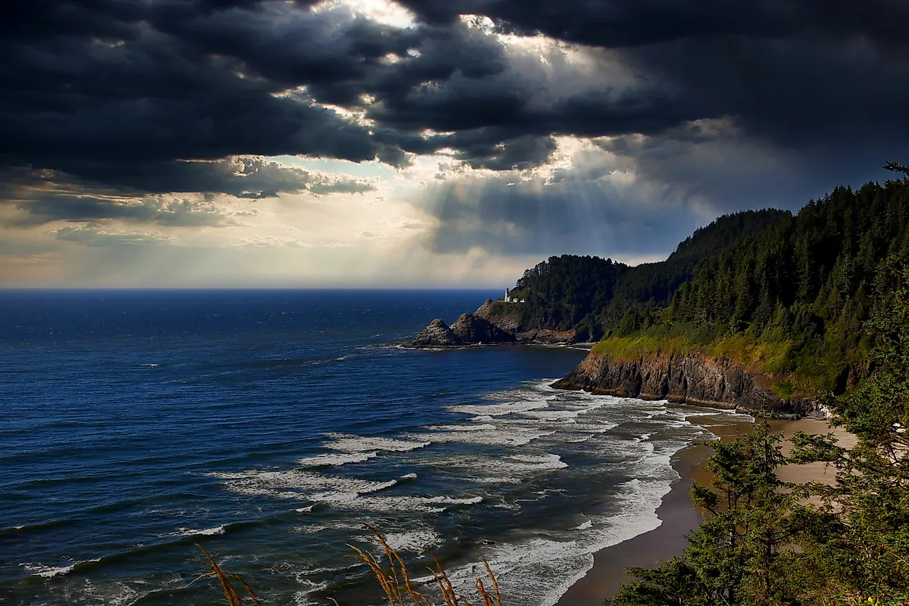 Light rays filter through storm clouds and illuminate the Heceta Head Lighthouse on the Oregon Coast.