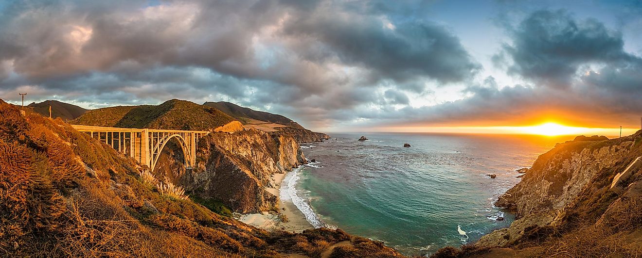 Scenic panoramic view of historic Bixby Creek Bridge along world famous Highway 1 in beautiful golden evening light at sunset with dramatic cloudscape in summer, Monterey County, California, USA