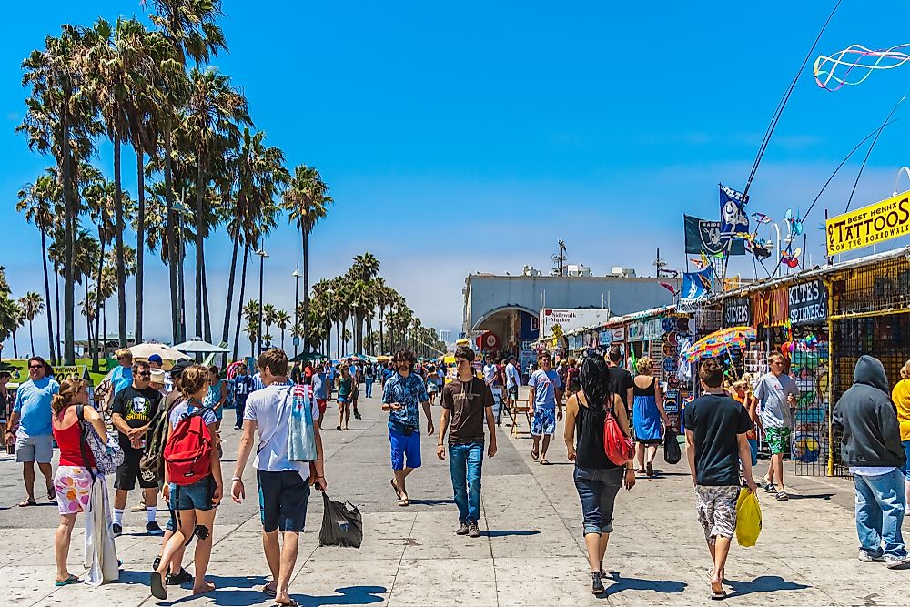 People walk the sidewalks in Venice Beach, California. Editorial credit: MattLphotography / Shutterstock.com.