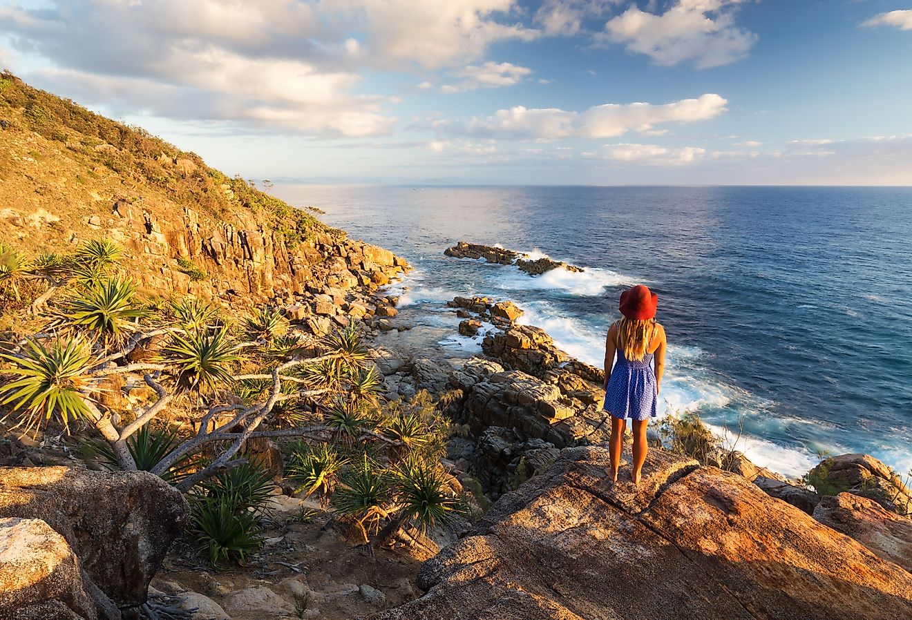 A young woman admires a coastal view at sunrise near Coffs Harbour, Australia.