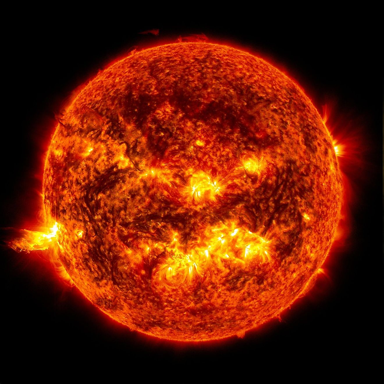 Solar flare on the left side of the sun and an eruption of solar material shooting through the sun’s atmosphere, called a prominence eruption