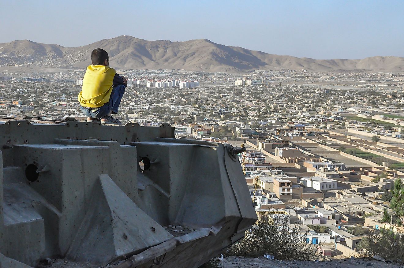 A boy sitting on a destroyed tank on the hills over Kabul City in Afghanistan. Editorial credit: Karl Allen Lugmayer / Shutterstock.com