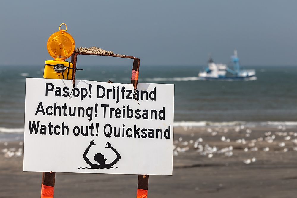 A sign warning of the danger of quicksand in multiple languages. 