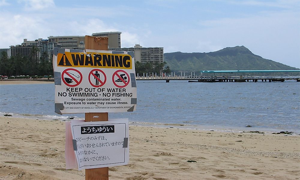 A sign warning people to stay away from sewage contaminated water.