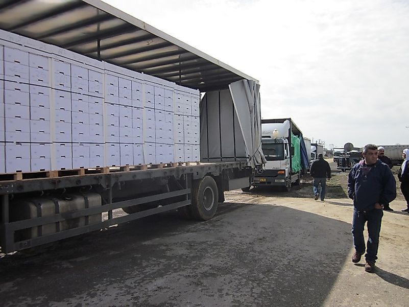 Trucks laden with export goods are transferred between Syria and Israel at the Quneitra Crossing.