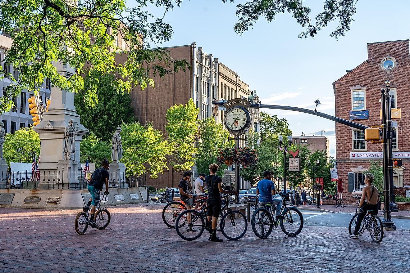 A group of male teenagers riding bikes on the city sidewalk.