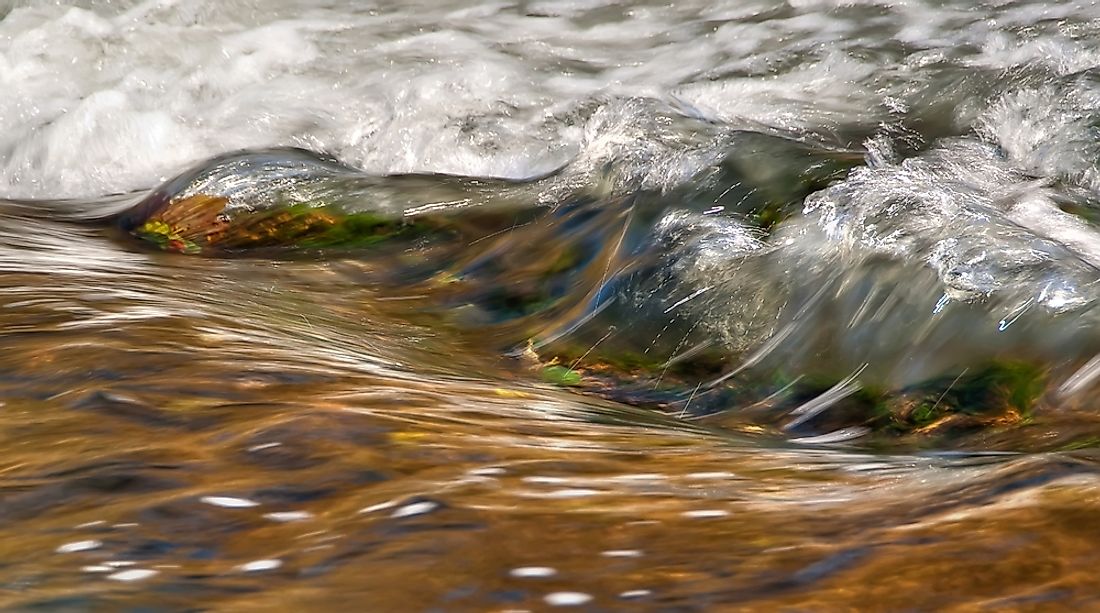 Water appears shallow and quick moving over a riffle due to sediment deposits.