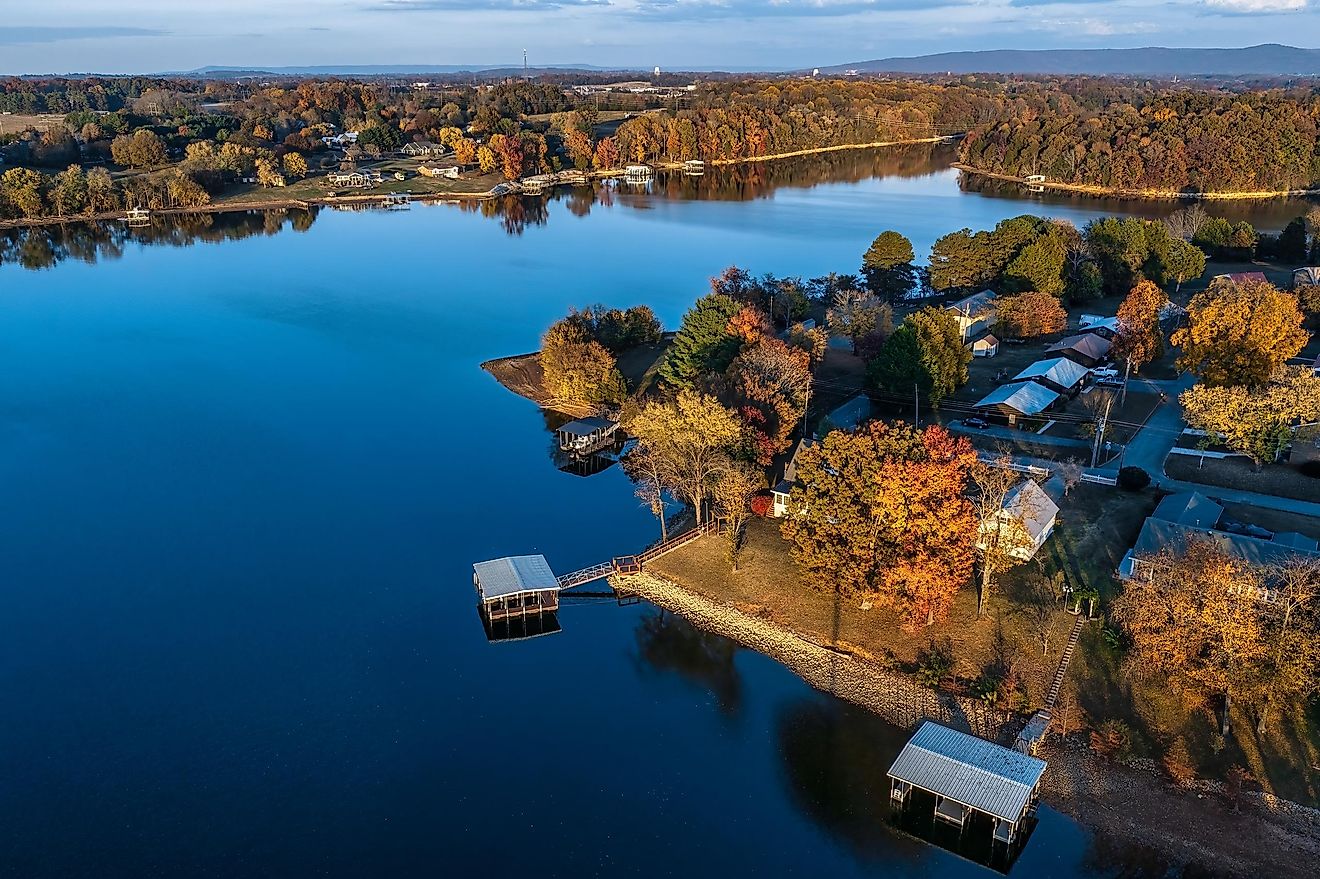 Aerial view of waterfront homes, boat docks and beautiful autumn foliage with mountains in the background on Tims Ford Lake in Winchester, Tennessee