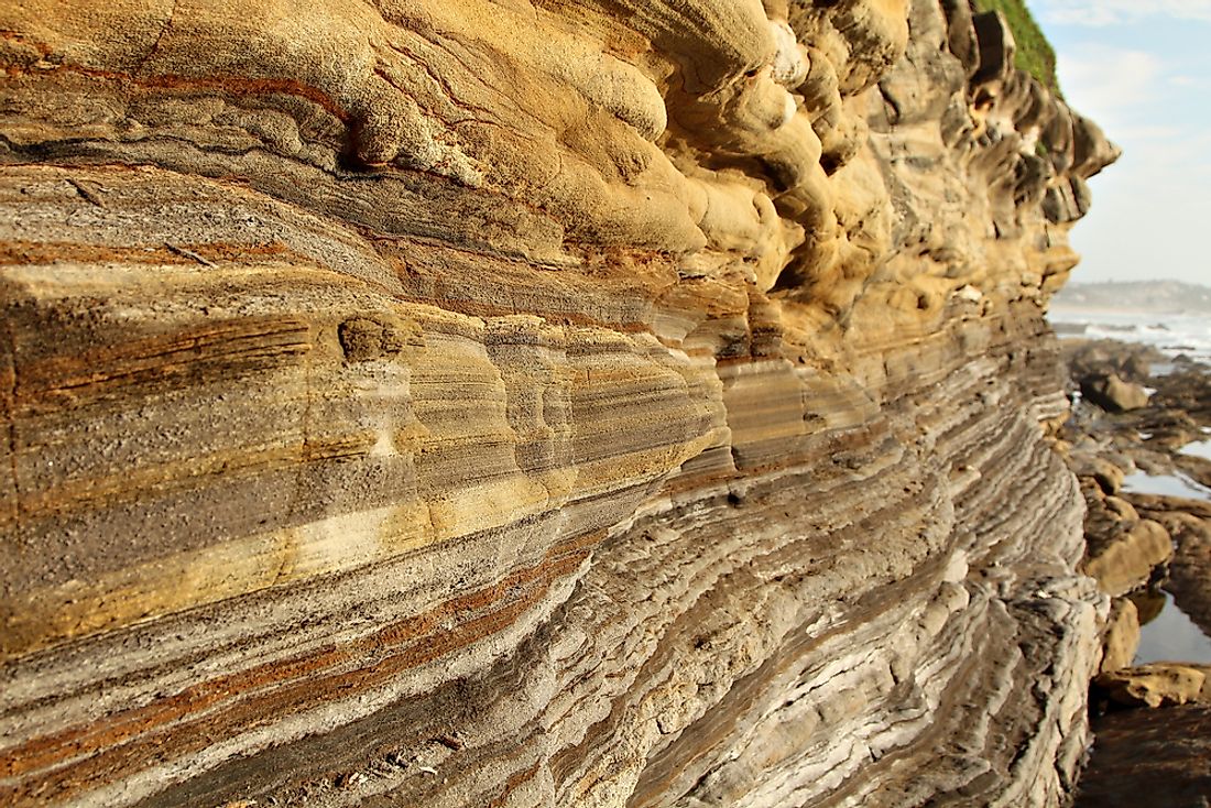 Oxidation gives sedimentary rock layers a reddish or orange color while organic material in the rocks may give layers a black or brownish color.