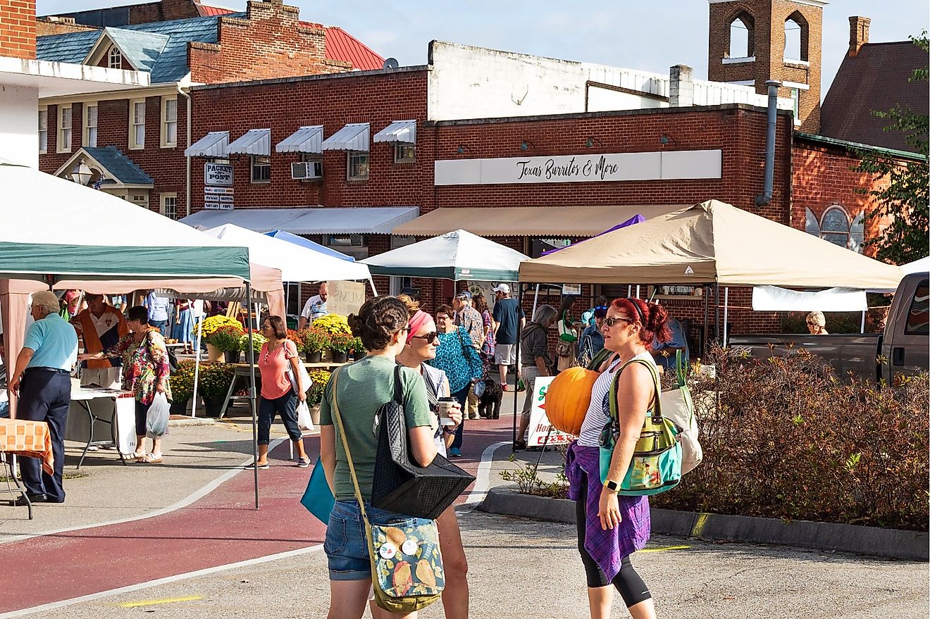 JONESBOROUGH, TN, USA-9/29/18: 3 women talk, while one holds a large pumpkin at Farmers' Market.