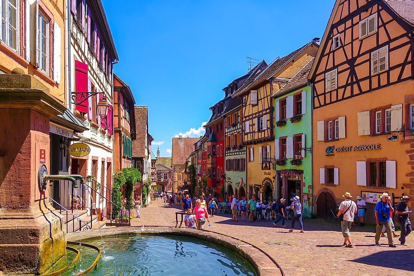 Tourists are walking on the main shopping street; Rue du General de Gaulle, in Riquewihr, Alsace wine road