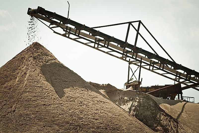 A massive conveyor sorts sand of various grain sizes as it moves.