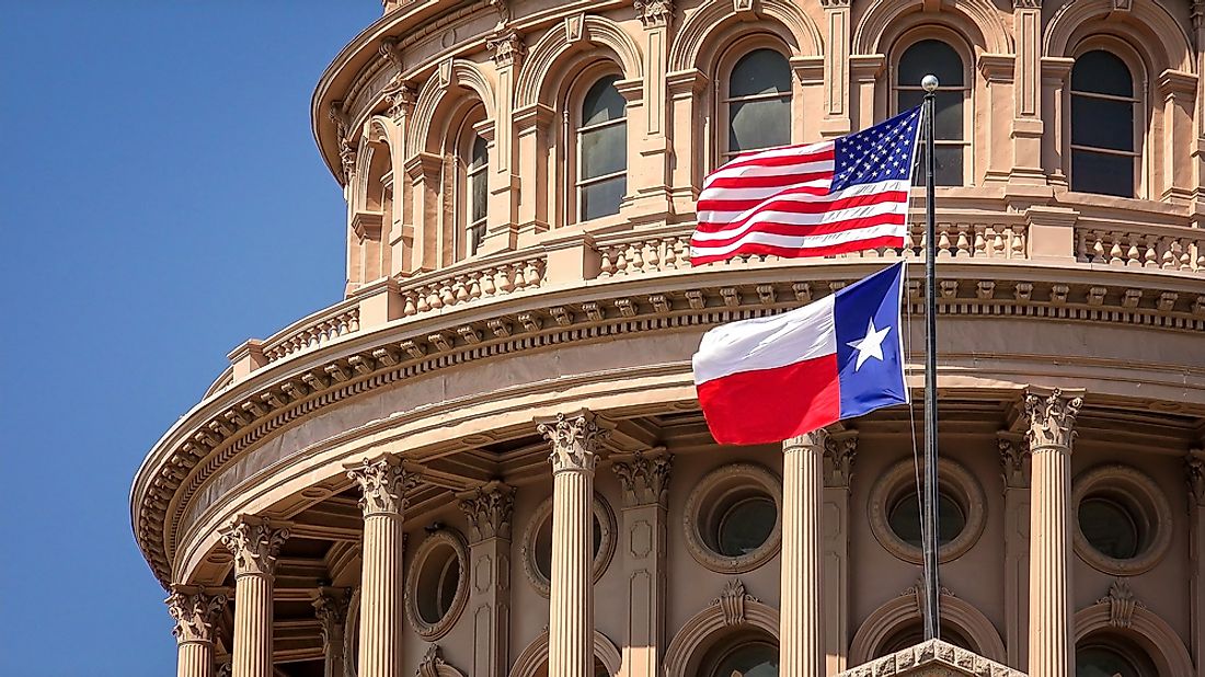 The Texas and American flags flying at the Texas State Capitol Building in Austin, Texas.
