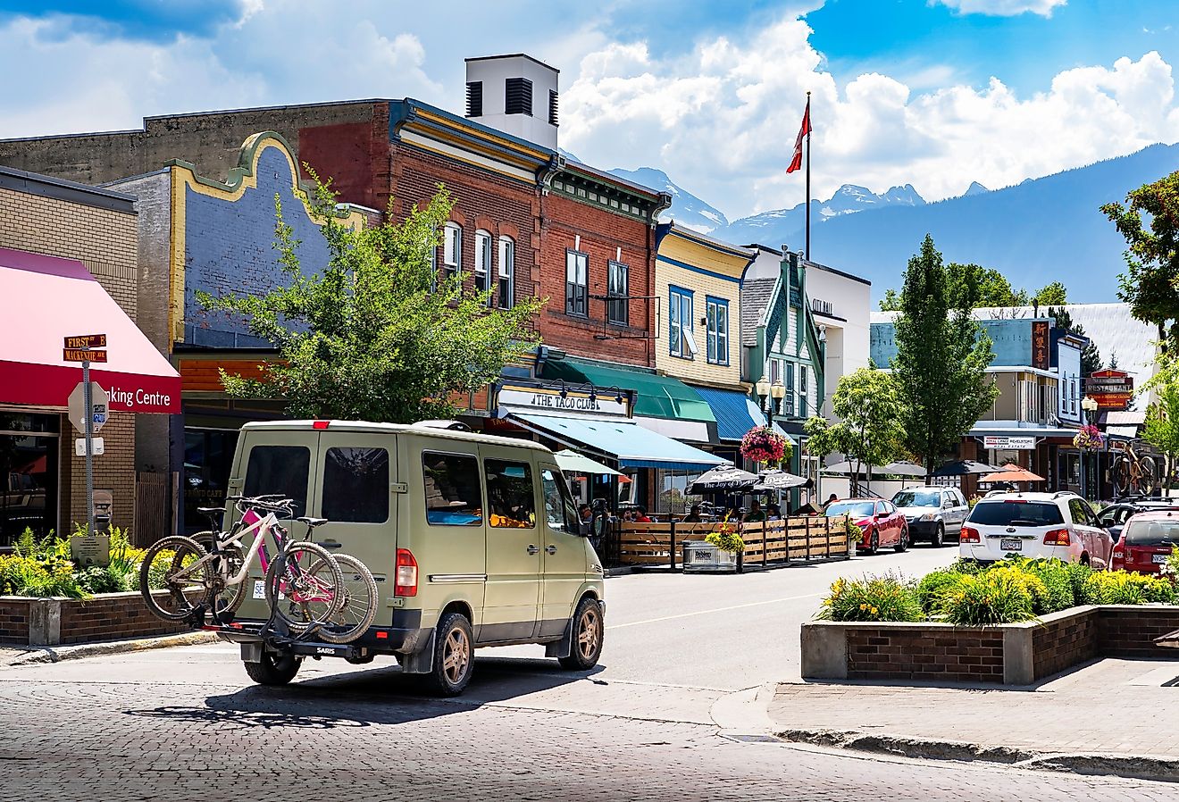 A camperized van with mountain bikes drives down the Main Street, with Selkirk Mountains in Revelstoke, British Columbia. Image credit Ramon Cliff via Shutterstock 