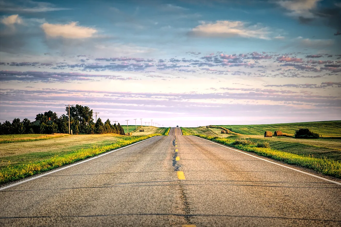 a long country highway rural highway road in North Dakota at sunset with a colorful sky. Editorial credit: adobe stock
