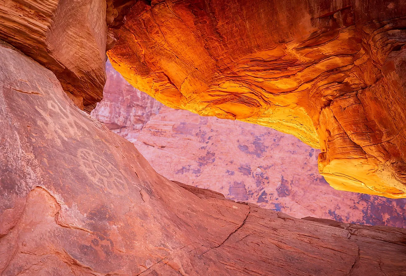 Petroglyphs on the dramatic red sandstone formation of Atlatl Rock with natural arch in Valley of Fire State Park Nevada.