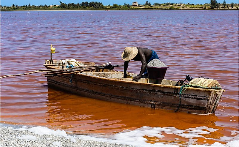 African man on the wooden boat over the Lake Retba or Lac Rose in Senegal.