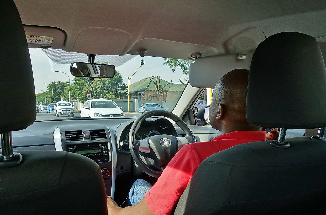 View of an Uber driver seen from the back seat in a car ride share in Johannesburg, South Africa. Image credit: EQRoy/Shutterstock.com